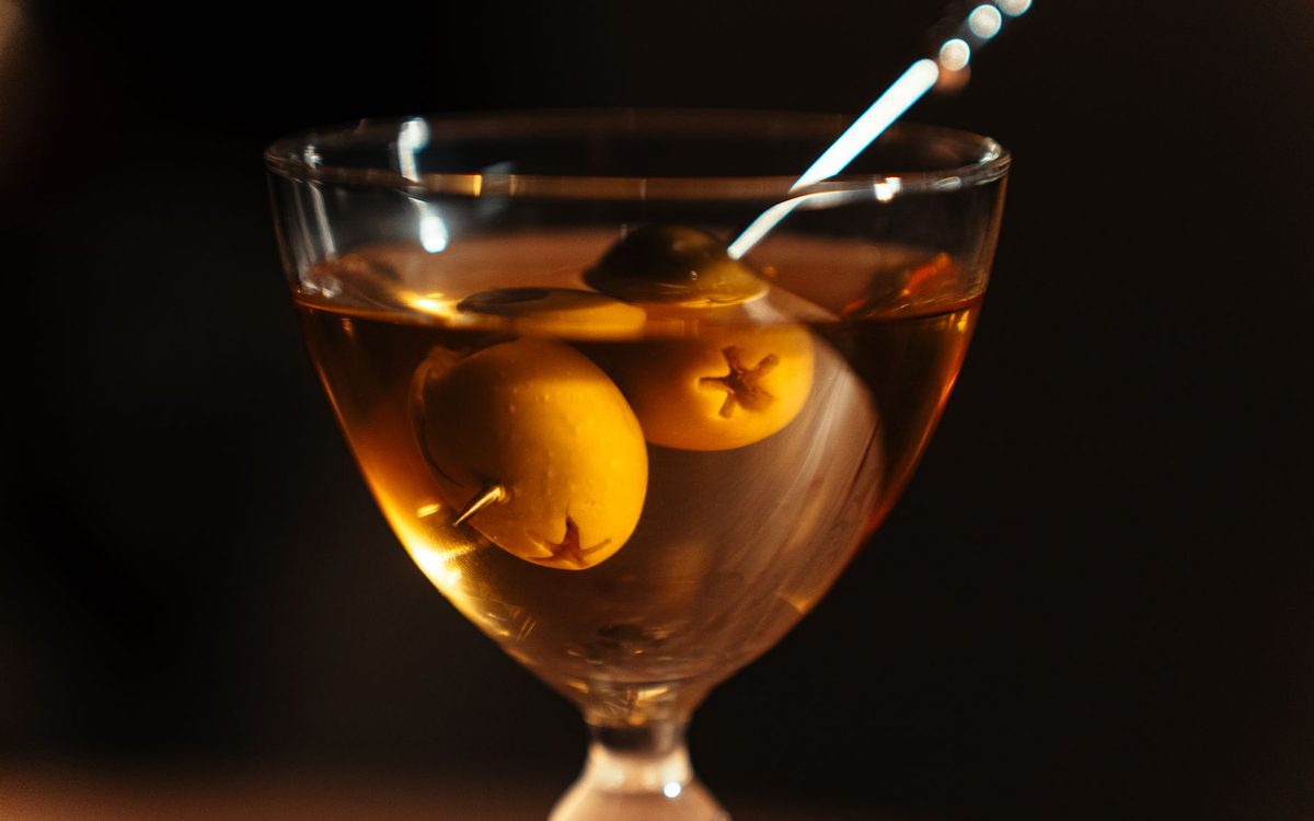 A stirred amber cocktail in a stemmed glass in a dark bar