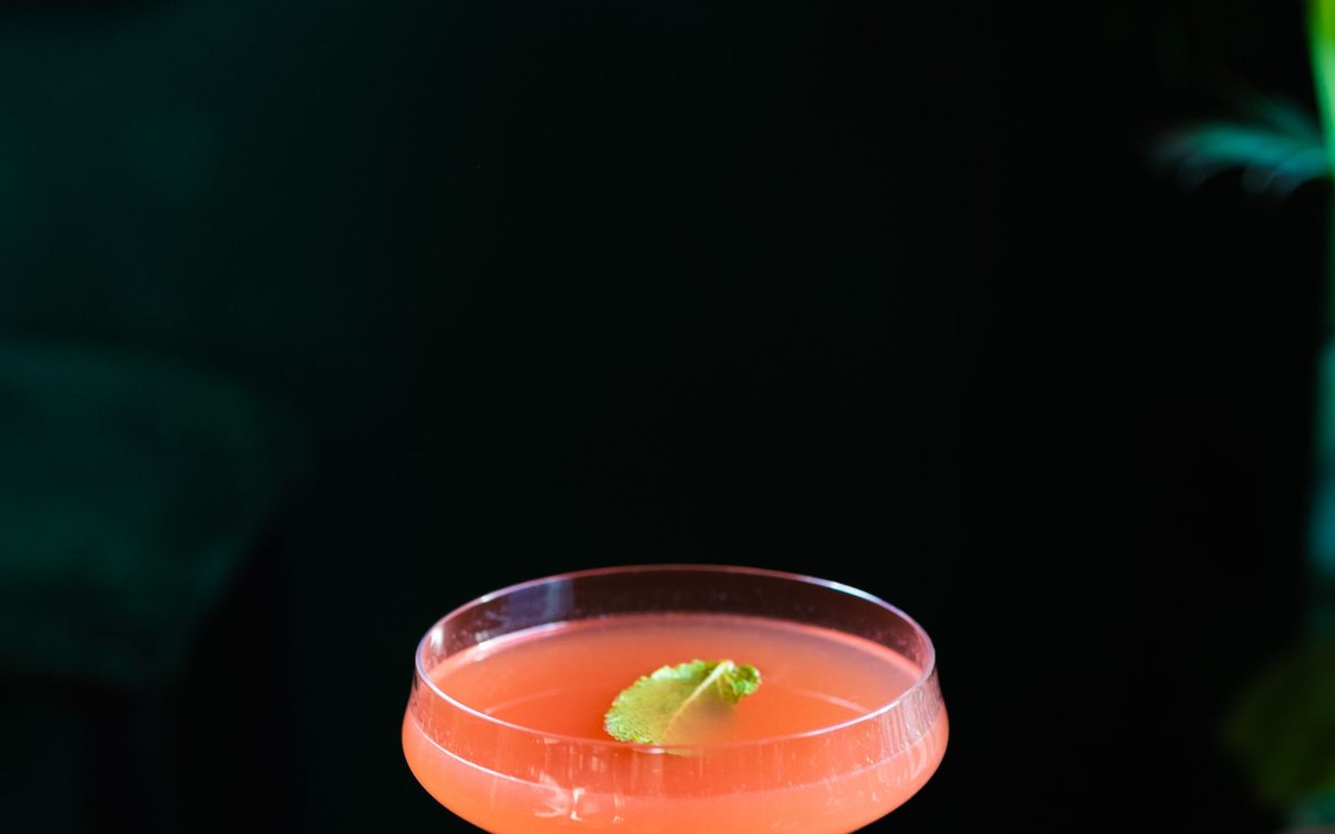 Pink cocktail in a coupe glass on a wooden table