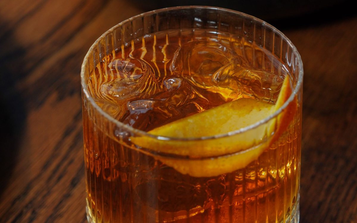 An Old Fashioned in a heavy rocks glass with an orange peel