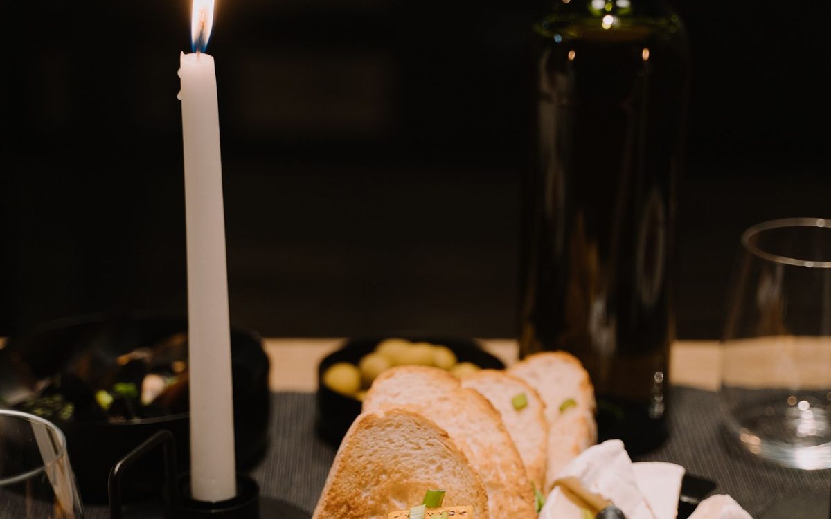Charcuterie board with cheese, grapes and bread by candlelight