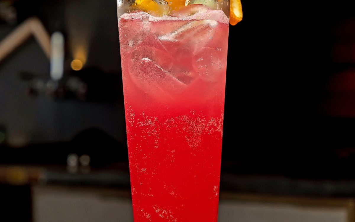Red tropical cocktail with pineapple and a cherry